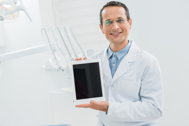 Dentiste montrant écran tablette vide clinique dentaire moderne
 - Photo, image