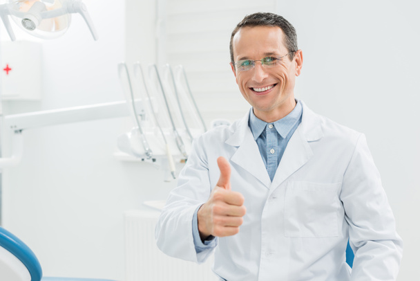 Hammaslääkäri osoittaa peukalo moderni hammashoitola - Valokuva, kuva