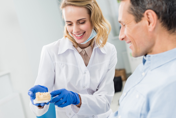 Médecin et patient regardant le modèle de mâchoires dans la clinique dentaire moderne
 - Photo, image