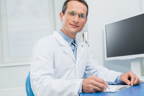 Doctor filling checklist by computer in modern clinic - Photo, Image