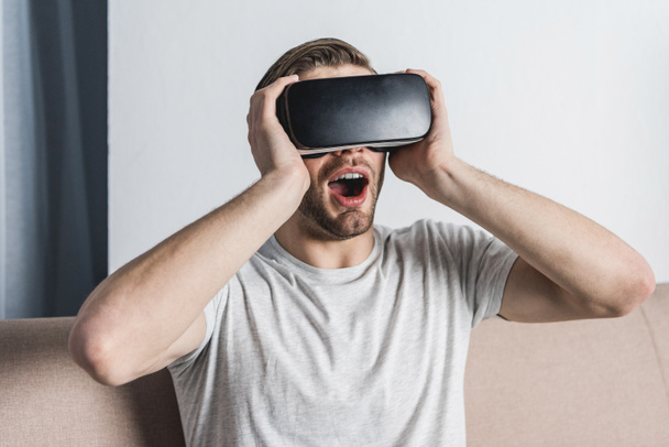 шокований молодий чоловік у гарнітурі віртуальної реальності
 - Фото, зображення