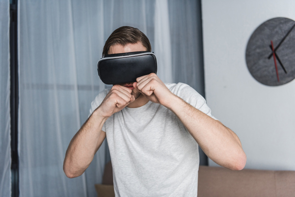 Jeune homme en réalité virtuelle casque jouer jeu de combat - Photo, image