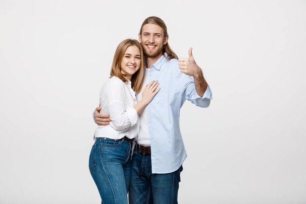portrét šťastný mladý pár ukazuje palcem nahoru izolované na bílém pozadí - Fotografie, Obrázek