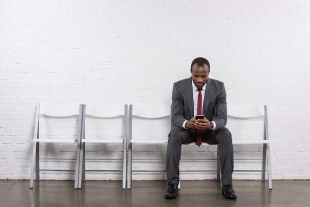 Африканский американский бизнесмен со смартфоном ждет собеседования
 - Фото, изображение