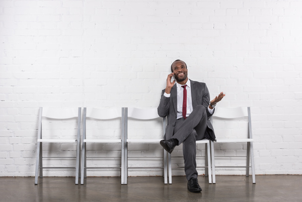 Africano americano empresário falando no smartphone enquanto espera por entrevista de emprego
 - Foto, Imagem
