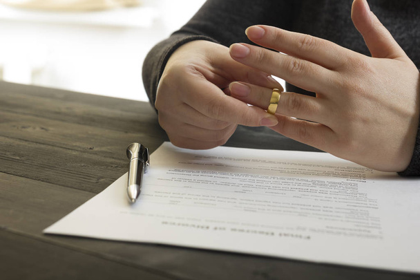 Handen van de vrouw, echtgenoot ondertekenen decreet van echtscheiding, ontbinding, annuleren van het huwelijk, juridische scheidingsdocumenten, het indienen van echtscheidingspapieren of voorhuwelijkse overeenkomst opgesteld door advocaat. Trouwring - Foto, afbeelding