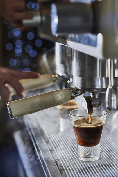 Barista macht einen Espresso mit einer klassischen italienischen Kaffeemaschine. - Foto, Bild