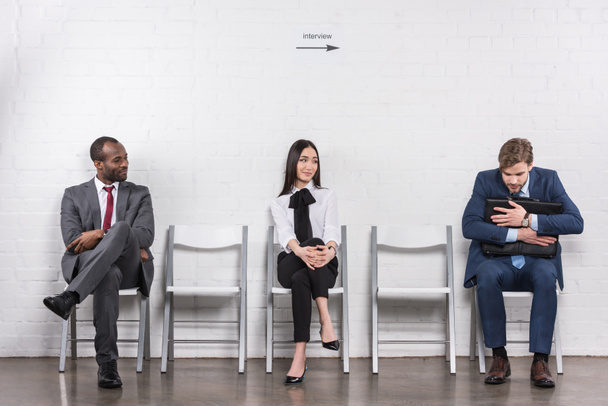 wieloetniczny młody biznes ludzi siedzi na krzesłach w oczekiwaniu na rozmowy kwalifikacyjnej - Zdjęcie, obraz