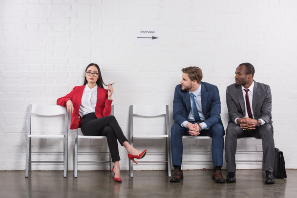 multicultural businessmen looking at asian businesswoman while waiting for job interview - 写真・画像