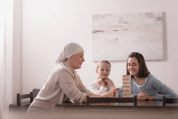 family of three generations playing with wooden blocks together, cancer concept  - Foto, imagen