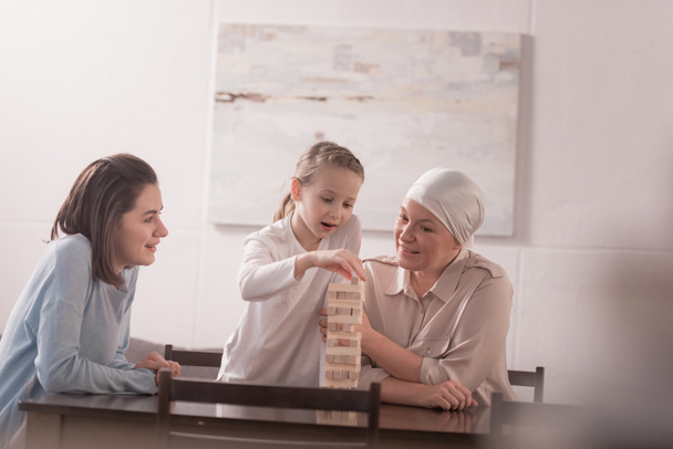 glückliche Familie aus drei Generationen, die gemeinsam mit Holzklötzen spielt, Krebskonzept  - Foto, Bild