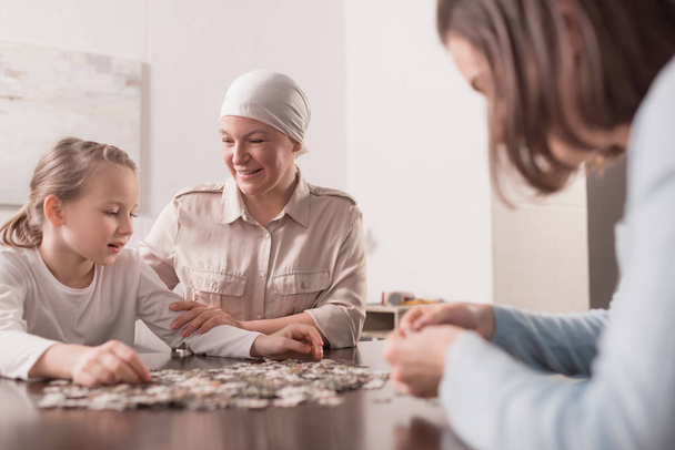 happy family playing with jigsaw puzzle together, cancer concept - Fotó, kép