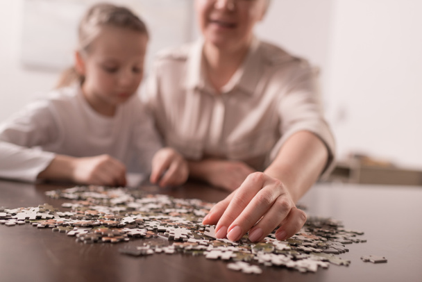 close-up view of grandmother and granddaughter playing with jigsaw puzzle together, cancer concept - Photo, image