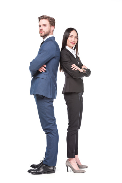 vista lateral de colegas de negocios multiculturales con los brazos cruzados parados espalda con espalda aislados en blanco
 - Foto, Imagen