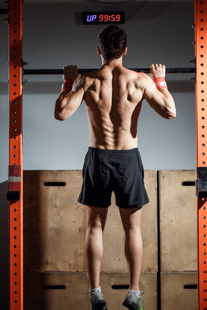 attractive young male adults doing pull ups on bar in cross fit training gym - Foto, imagen