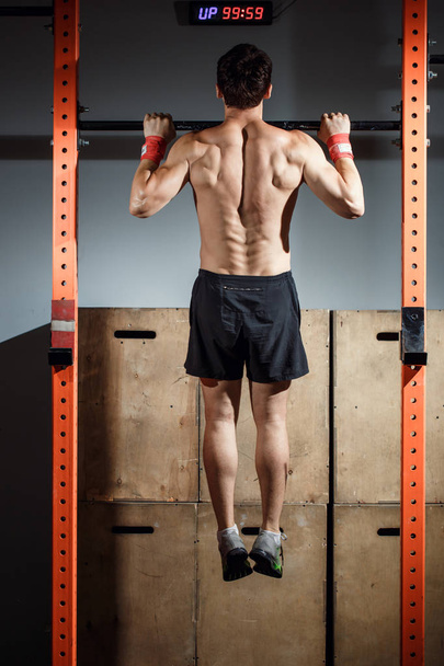 attractive young male adults doing pull ups on bar in cross fit training gym - 写真・画像