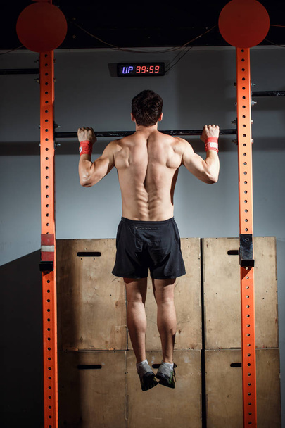 attractive young male adults doing pull ups on bar in cross fit training gym - Foto, Imagem