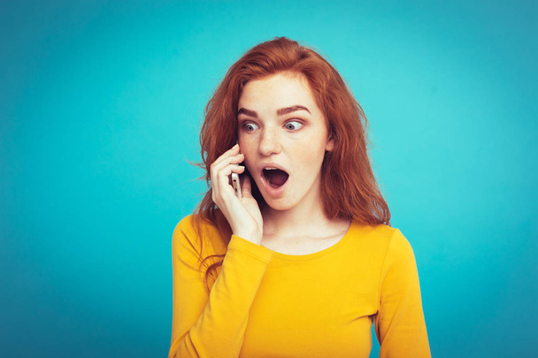 Lifestyle and Technology concept - Portrait of cheerful happy ginger red hair girl with joyful and exciting talking with friend by mobile phone. Isolated on Blue Pastel Background. Copy space - Photo, Image