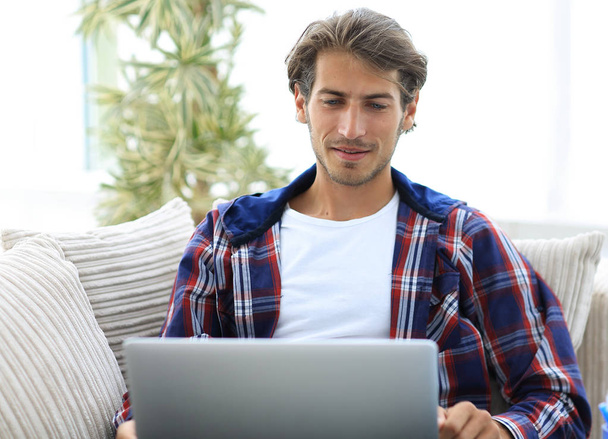 happy successful young man looking at laptop at home. - Фото, изображение