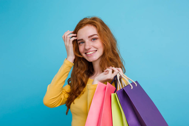 Koncepcja zakupy - bliska portret młody piękny redhair atrakcyjna dziewczyna uśmiechając się, patrząc na aparat z torby na zakupy. Niebieskim tle Pastel. Miejsce - Zdjęcie, obraz