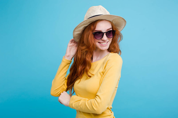 旅行の概念 - トレンディな帽子とサングラス笑みを浮かべて肖像若い美しい魅力的な redhair 女の子を閉じる。青いパステル背景。コピー スペース - 写真・画像