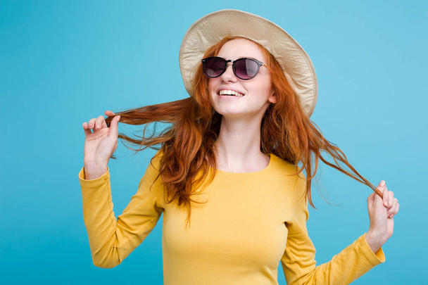 Travel concept - close-up portret jonge mooie aantrekkelijke redhair meisje met trendy hoed en zonnebril glimlachen. Blauwe Pastel achtergrond. Kopiëren van ruimte - Foto, afbeelding