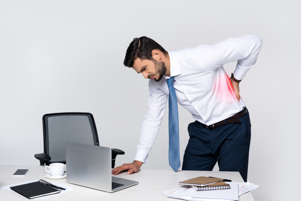 giovane uomo d'affari che soffre di mal di schiena mentre si appoggia a tavola con computer portatile
 - Foto, immagini