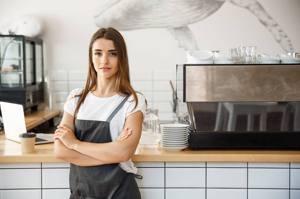 Café Business proprietário Conceito - Retrato de feliz atraente jovem bela barista caucasiano em avental com olhar confiante para a câmera no balcão da cafetaria
. - Foto, Imagem