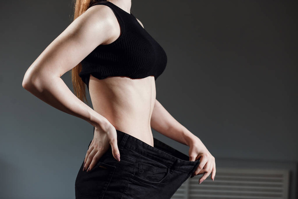Slim Woman with healthy thin body,showing her old jeans after successful diet. - Photo, Image
