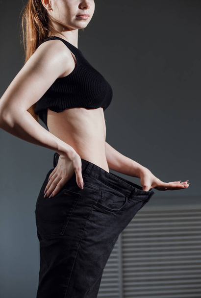 Slim Woman with healthy thin body,showing her old jeans after successful diet. - Valokuva, kuva