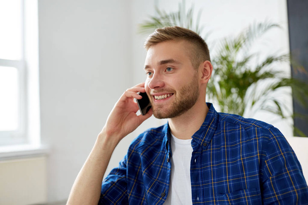 giovane uomo sorridente che chiama sullo smartphone in ufficio
 - Foto, immagini