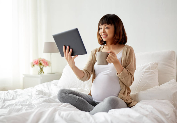 happy pregnant asian woman with tablet pc at home - Foto, imagen