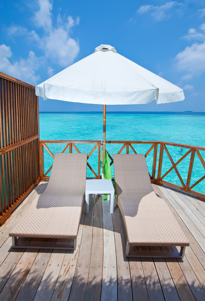 Parasol and chaise lounges on a terrace of water villa, Maldives. - Photo, Image