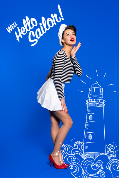 beautiful young woman in sailor shirt with lighthouse drawing and well hello sailor inscription isolated on blue - Photo, Image