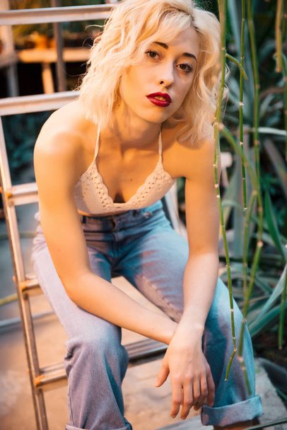 Retrato de una joven atractiva sobre una escalera en la vegetación
 - Foto, imagen