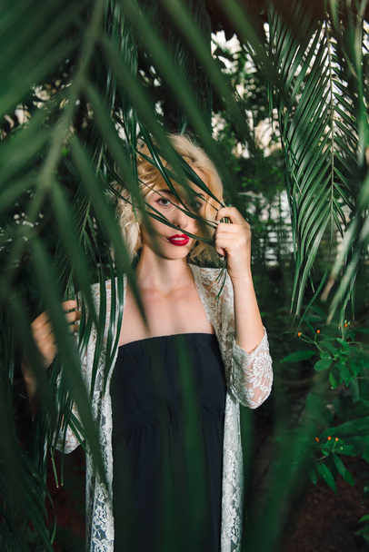Misteriosa mirada del modelo femenino mirando a través de las ramas de la palma
 - Foto, Imagen