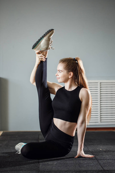 Beautiful slim brunette doing some stretching exercises in a gym - Valokuva, kuva