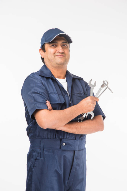 Mecánico indio feliz auto en traje azul y tapa que sostiene la herramienta de la llave en acción, aislado sobre fondo blanco
 - Foto, Imagen
