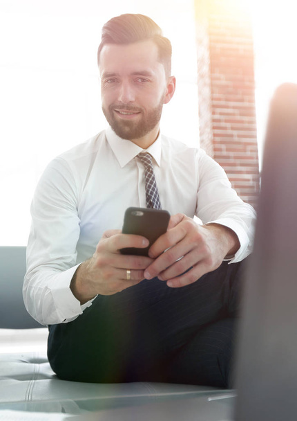 businessman holding a smartphone and looking at the camera - Fotoğraf, Görsel