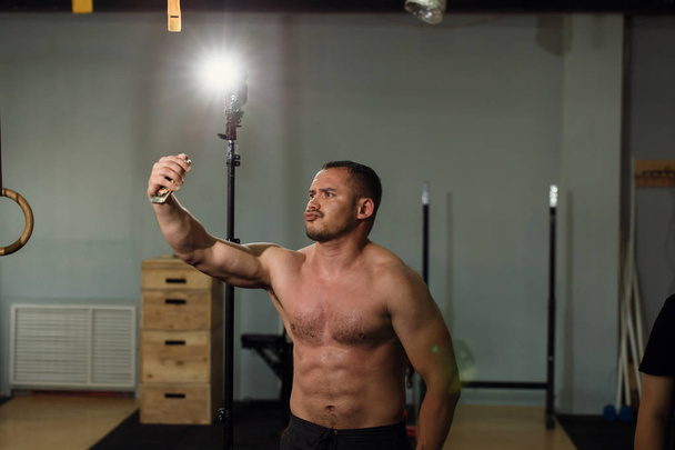 Handsome shirtless muscular bodybuilder man taking selfie with cell phone - Photo, Image