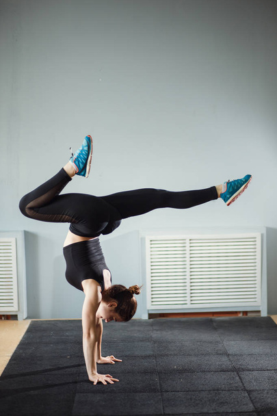 woman working out against grey wall, doing yoga or pilates exercise - Foto, afbeelding