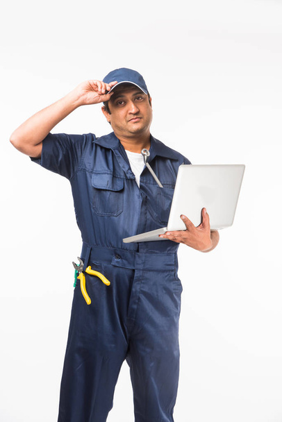 Indiano feliz auto mecânico em terno azul e tampa segurando ferramenta de chave em ação, isolado sobre fundo branco
 - Foto, Imagem