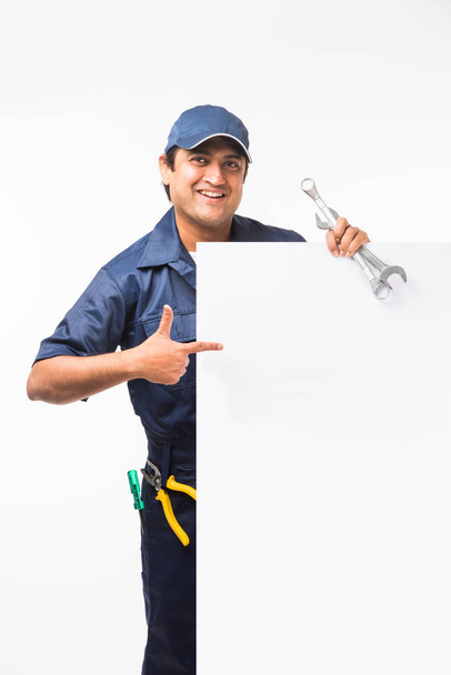 Indian happy auto mechanic in blue suit and cap holding spanner tool in action, isolated over white background - Φωτογραφία, εικόνα