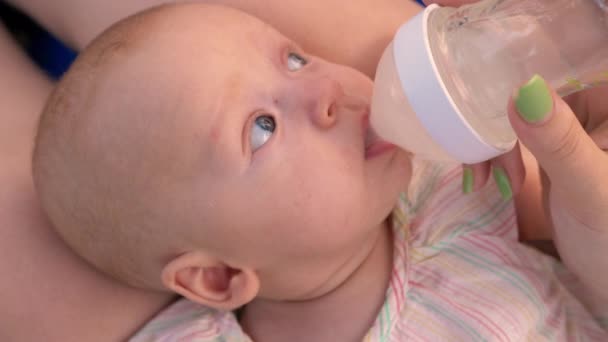 Mom giving baby to drink water from the bottle - Imágenes, Vídeo