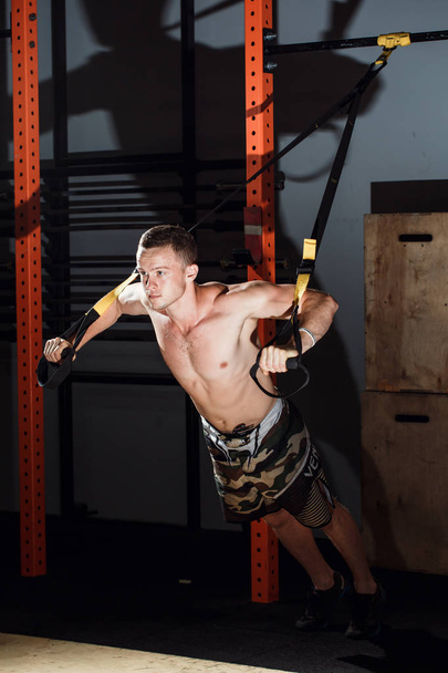 men doing push ups training arms with trx fitness straps in the gym - 写真・画像