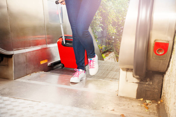 Womens shoes and red suitcase going up on the escalator outdoors - 写真・画像