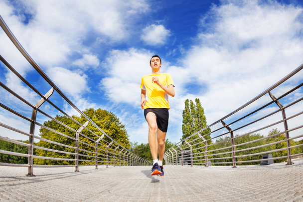 Active man running sprinting across the bridge outdoors in summer - Foto, imagen