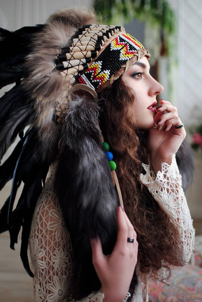 Amerikanische Ureinwohnerin. Indianer Amerikas. Federn auf der Kopfbedeckung. Amerikanischer Stil. Stilvolles Mädchen. Lebensstil. Perlen. - Foto, Bild