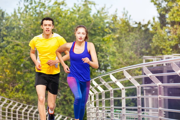 Két sportos emberek, fiatal férfi és nő, nyáron szabadtéri edzés alatt futó portréja - Fotó, kép