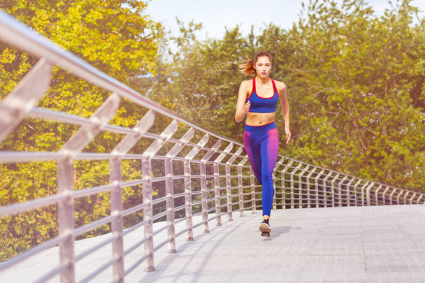 Sporty young woman jogging and exercising in the park at sunny day - Foto, Imagem
